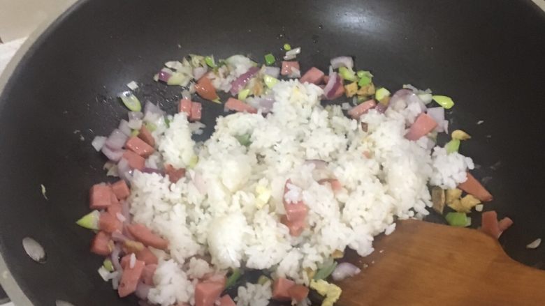 炒饭秀家常炒饭,放入米饭,可以看到米饭放在冰箱里冻成块,用铲子将其铲碎。也可预先使用锅铲或勺子处理碾碎。如果选择直接在锅里处理米饭期间,最好使用最小火以免糊锅。小火加热也有助于分离大团饭块。