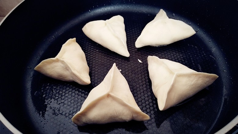 早餐+三角生煎包,锅中刷一层油,烧热锅底,摆放包子,盖上锅盖醒发片刻。