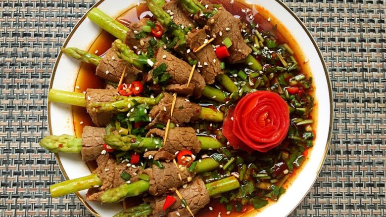 凉拌芦笋牛肉卷,将芦笋牛肉卷摆入盘中,浇上料汁,撒上白芝麻,再用番茄皮卷花装饰一下!