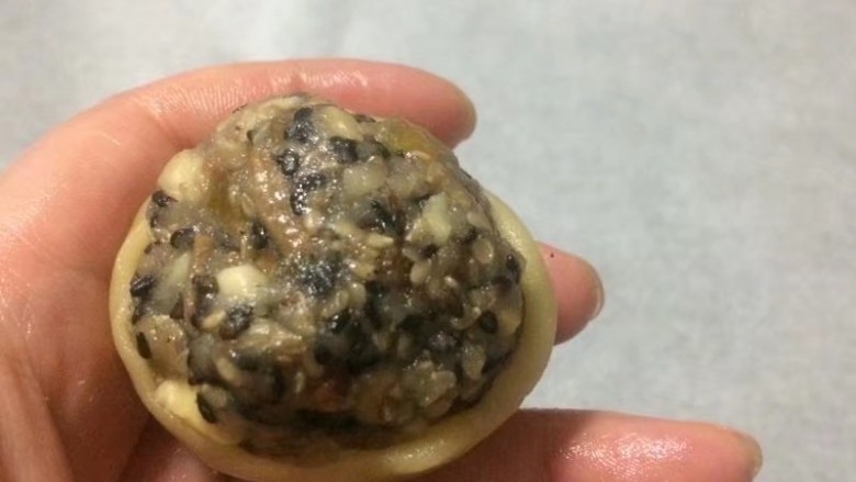 金秋玫瑰五仁月饼,取一个月饼皮手心按扁,中间薄边缘厚,包入一个五仁馅