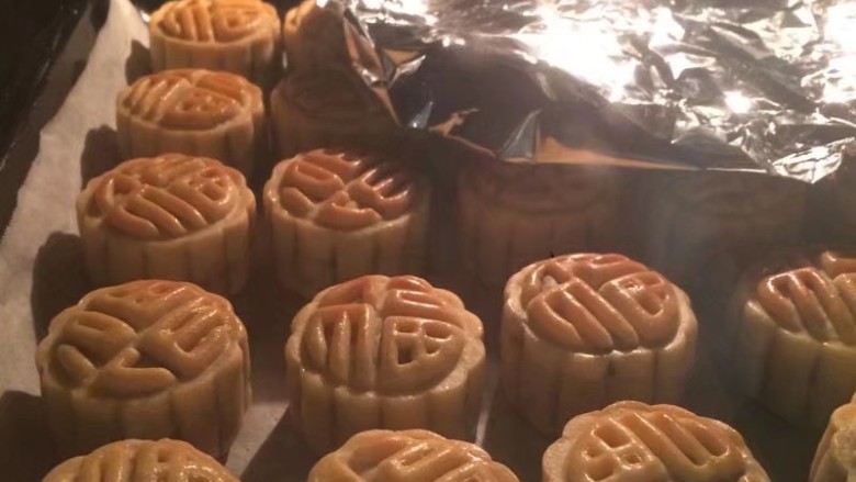 金秋玫瑰五仁月饼,一共烤20分钟,中途每隔五分钟取出刷一遍蛋黄液,我家烤箱红外烤有点不均匀,所以颜色深的区域我用锡纸盖一下,让颜色浅的月饼继续上色,微黄上色就可以,不可烤太久