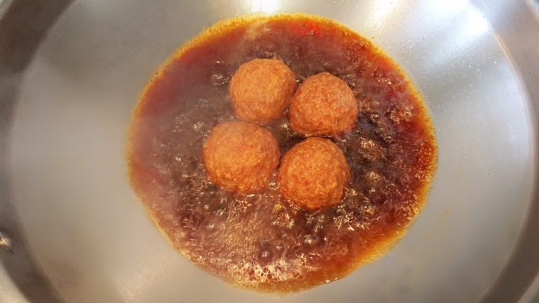 红烧狮子头,锅中倒少量油,放入炸好的肉圆,待油温升高后加入少量酱油,三秒后,加没过食材的开水,然后放入盐糖鸡精调味;水滚后改小火炖十五分钟;最后收汁即可出锅;烹饪过程中汁水减少,也可用锅铲将汁水浇于肉圆表面,此时狮子头还差一步哦;