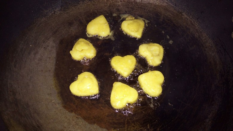 爱心土豆饼,锅里倒入油,烧成七八成热,倒入爱心土豆饼,小火油炸,炸至黄色,翻面,炸好后,捞出控油