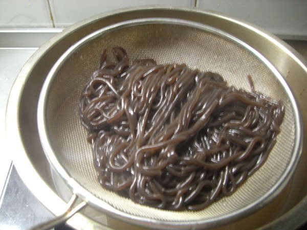黯然酸辣蕨根粉,5.用漏勺捞出,放在清水中过凉。用筷子轻挑几下,防止蕨根粉粘连。