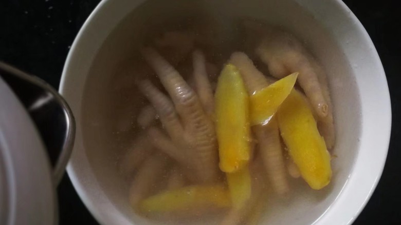 柠香泡椒凤爪,煮好的鸡爪放入大碗里,其他配料都不要留下生姜,倒入凉白开没过鸡爪浸泡一下。