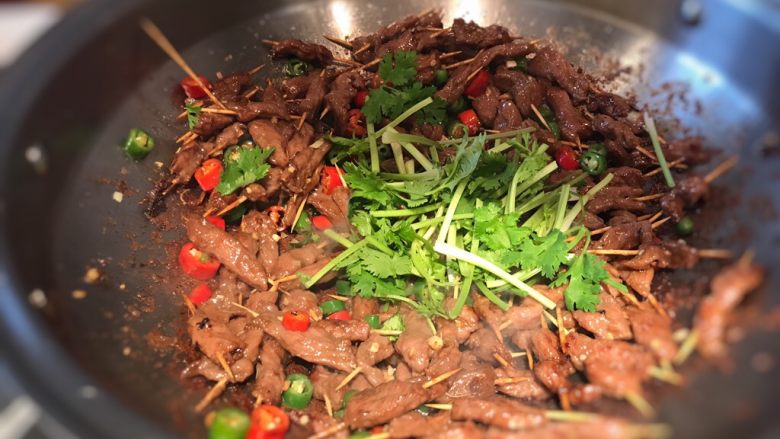 孜然牙签牛肉,加入一半香菜翻炒均匀,香菜不要太早下锅,不然很容易蔫掉哦;