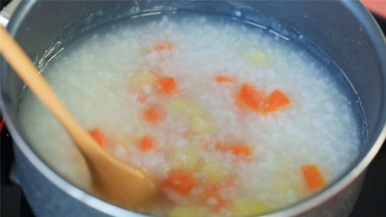 胡萝卜土豆鸡肉粥,蒸好的胡萝卜、土豆放入粥中搅拌均匀,继续熬煮。