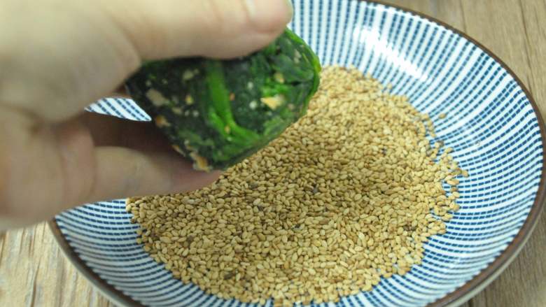 绿色美食麻酱果仁菠菜,取出菠菜,一头蘸上芝麻,另一面也蘸上芝麻
