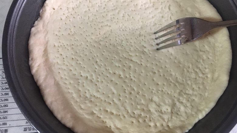 意式鲜虾烟熏香肠披萨,铺入披萨盘中,四周推厚,形成自然的卷边。并用叉子叉出均匀的孔。