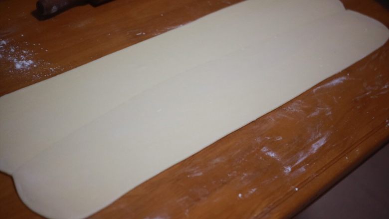 丹麦手撕吐司,用走锤顺着接缝的方向擀开,擀至0.5cm厚左右,擀开的时候要注意用力均匀,使黄油分布均匀,台面上要撒粉防粘