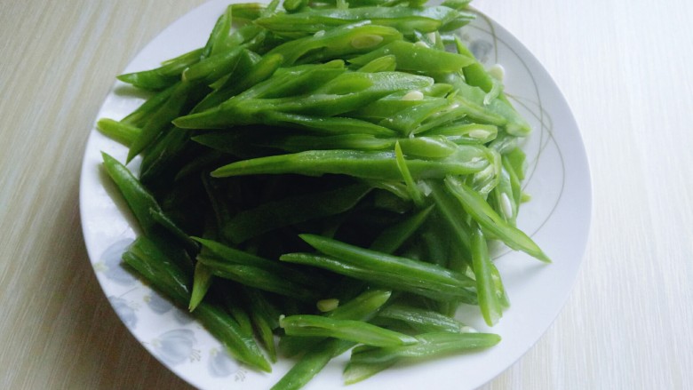 绿色美食+香炒翠绿豆角丝,全部切好的豆角丝装入盘中备用。