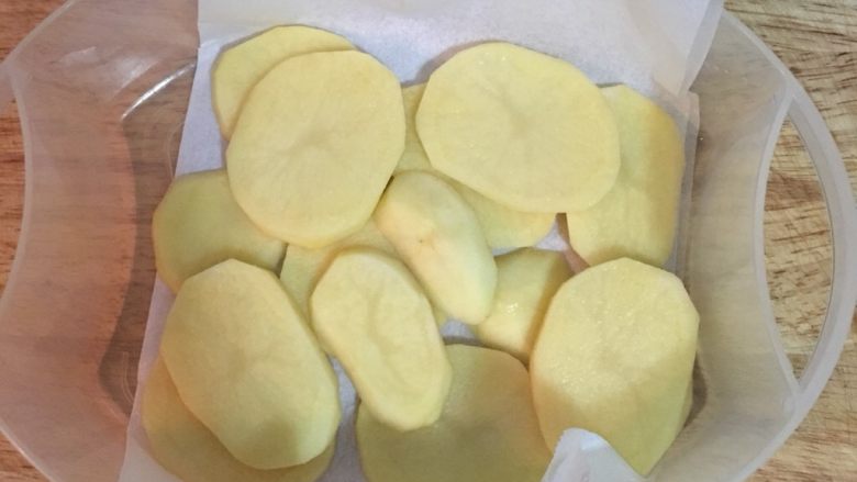 剁椒蒸土豆鸡胸,蒸盆下先铺一张烘焙纸,方便等一下蒸好后移盘,又或者如果蒸笼裡放的下盘子,就可以直接摆放在盘子裡去蒸;在烘焙纸或盘裡先排上用盐抓过的土豆片,