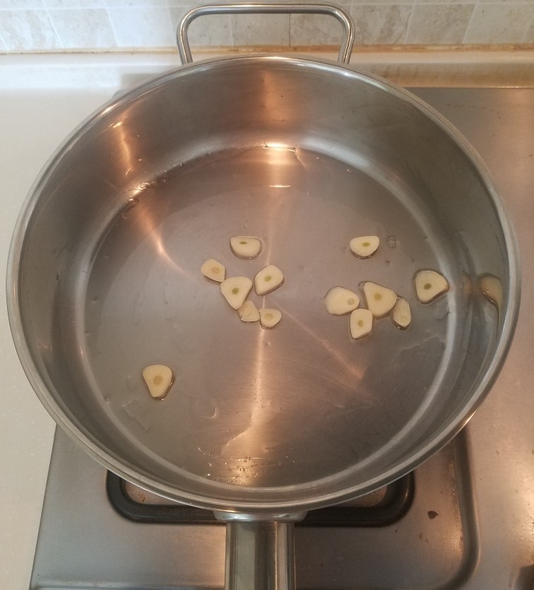 泡菜锅,锅里倒一大勺食用油用中火加热,放入蒜片煽炒出香味。