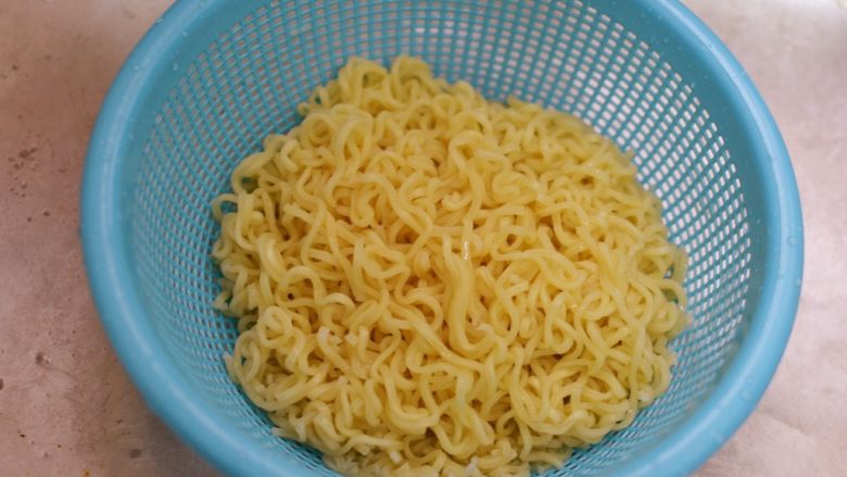 炒方便面,这个时候面煮好了。倒出来过冷水,可以防止粘黏。再沥干水分。