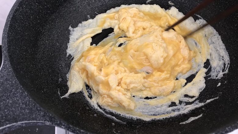 绿色美食~苦瓜炒蛋,蛋液开始凝固时,筷子顺一方向打圈,直到全部凝固(这样炒出来的蛋花比较蓬松饱满有弹性哟)