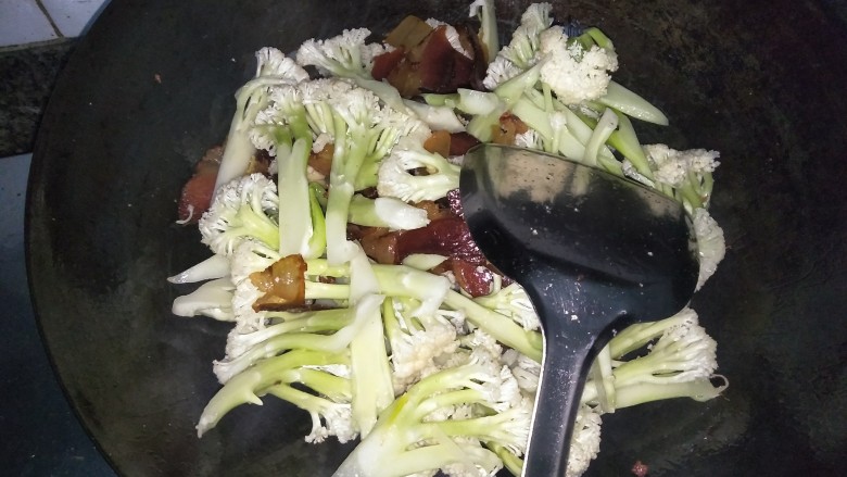 酱肉花菜,调大火，倒入洗净切好的花菜，翻炒均匀，加入盐，少量醋和少量老抽（酱肉和腊肉大多偏咸，所以盐和老抽的量比平时稍微减量）