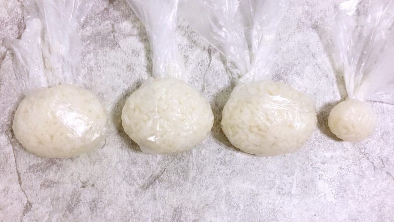 小女孩饭团,1⃣️把米饭放到保鲜袋中捏成椭圆形,做成小女生的脸,再捏一个小饭团做成丸子头。