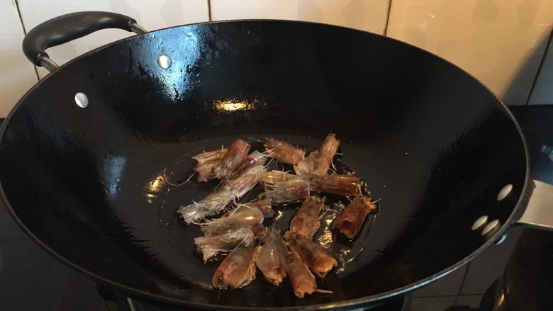 只用家常调料，成就鲜美浓郁的大虾年糕,热锅凉油，下虾头，转小火慢慢熬出虾油。这个过程中，总锅铲背轻轻压压虾头，把虾黄挤出来。