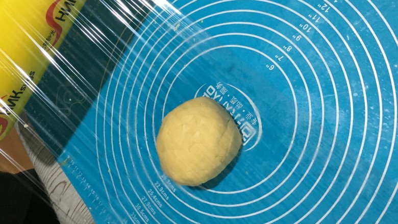 万圣节“捣鬼”糖霜饼干,捏好的面团,放在硅胶垫上,上面盖上保鲜膜。