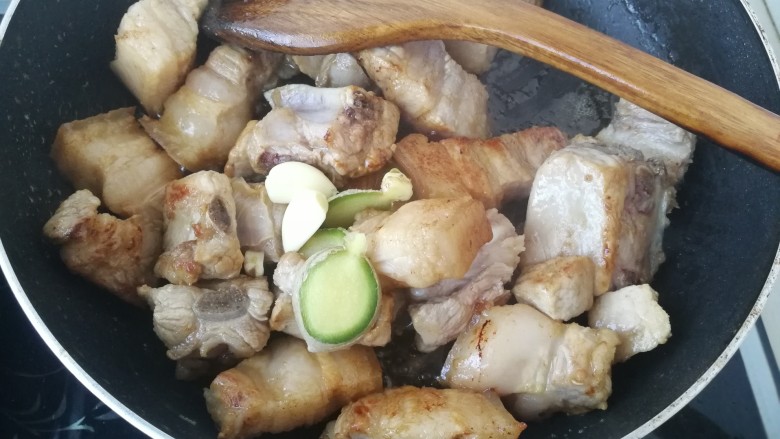 #那一抹家乡味#妈妈菜干豆角烧肉,继续加入一些蒜瓣和和<a style='color:red;display:inline-block;' href='/shicai/ 2800'>生姜</a>,中火翻炒。
