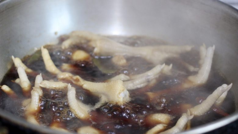 蒜泥凤爪,煮沸后转小火至凤爪9成熟。再在汤水汁里泡两小时,让凤爪上色。余温让凤爪全熟。