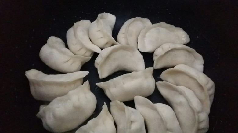 冰花煎饺,把饺子摆上。启动电饭煲的柴火饭功能,盖上盖子煎5分钟。(因为猪肉是熟的,所以不用煎太久。)