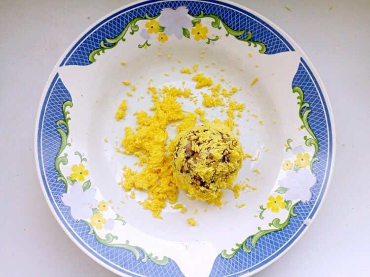 彩色饭团,将一份米饭团成饭团,逐个在蛋黄中打滚儿,让表面沾满蛋黄。