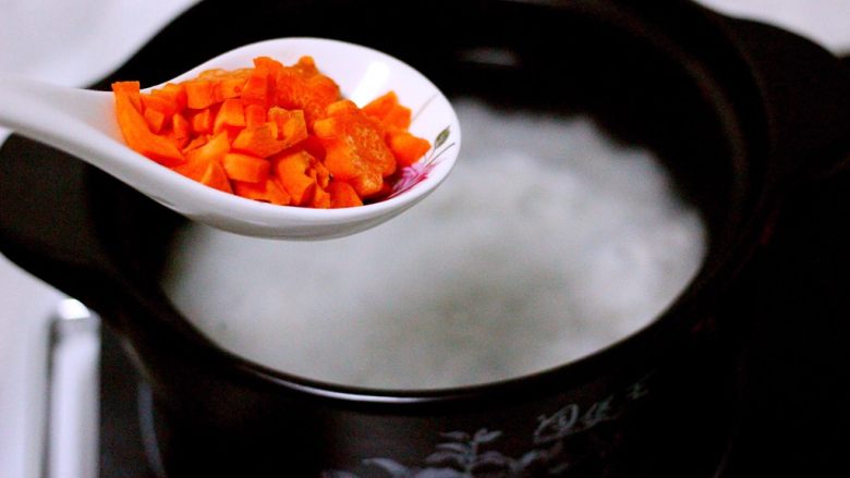 剩米饭也有春天(海鲜杂蔬粥),砂锅里的米饭煮沸后、加入胡萝卜丁