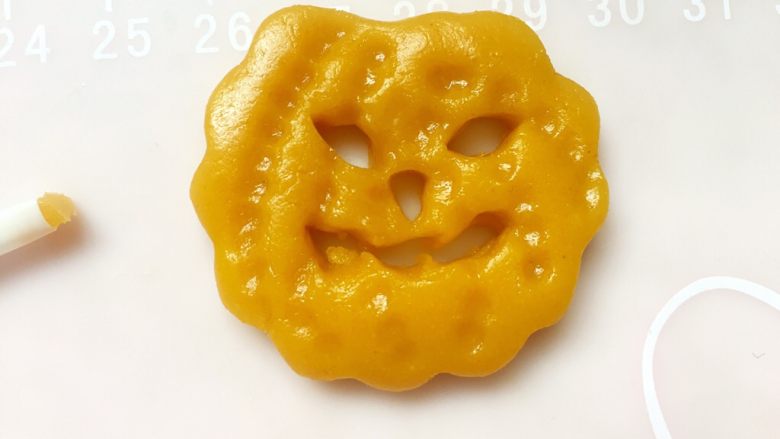 万圣节-南瓜鬼脸饼干,用粗的吸管按压吸捏出眼睛和嘴巴,用细的吸管按压吸捏出鼻子。