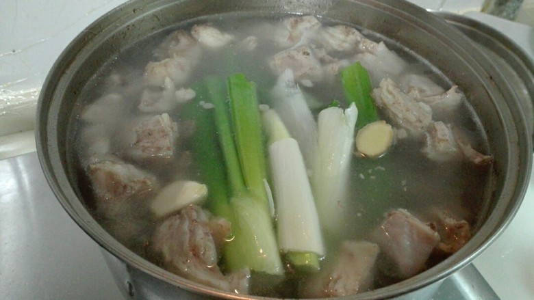 羊油香飘羊排汤,羊排锅烧开了,撇去浮沫,放进大葱,姜片,<a style='color:red;display:inline-block;' href='/shicai/ 2795'>蒜头</a>,八角和花椒纱布包烧开,调小火慢炖两个小时