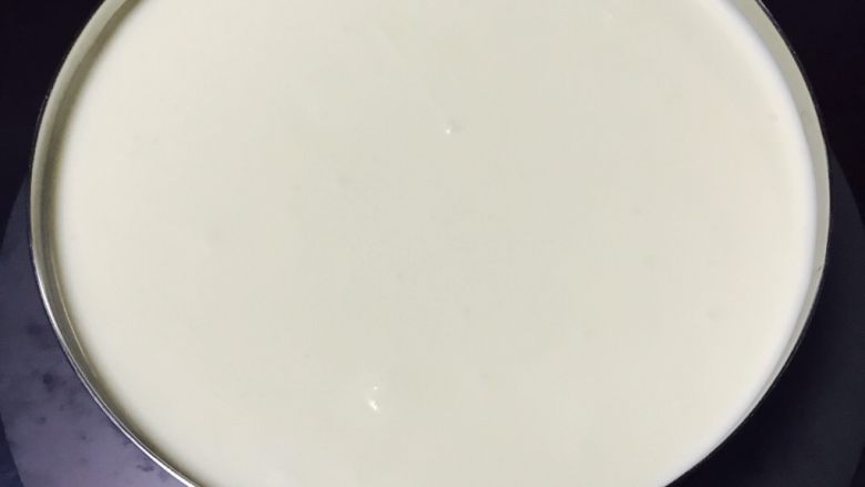 百香果芝士慕斯蛋糕,取出冰箱冷藏的饼底,把奶酪倒入慕斯圈中,轻轻振几下,抖出气泡。放进冰箱冷藏6小时以上,我是晚上做的,正好放一整个晚上。