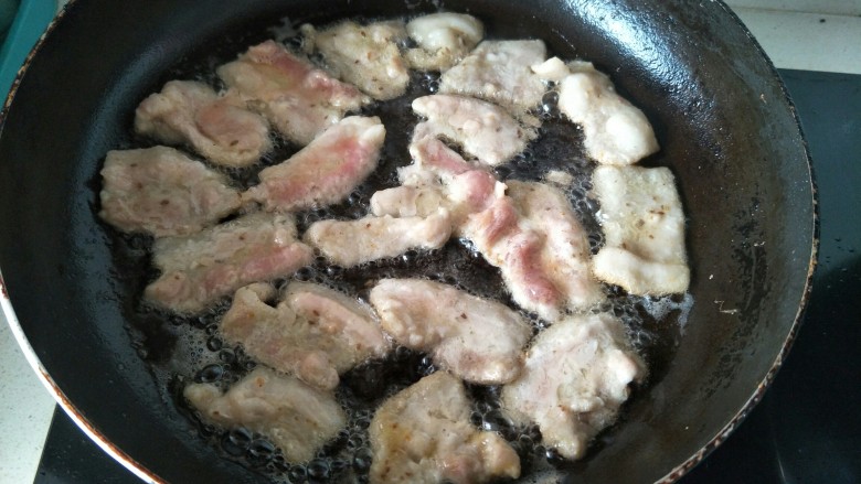 煎炸小酥肉,平底锅放油加热,用筷子夹起腌制好的肉片一片片平铺煎炸。