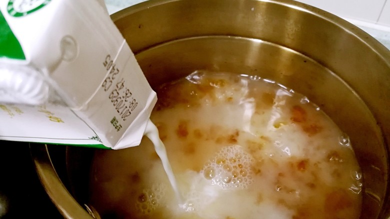 桃胶木瓜炖奶 #冬喝暖饮夏吃冰#,倒入牛奶,继续小火慢煮。