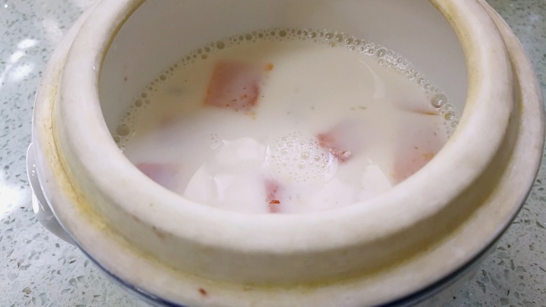 桃胶木瓜炖奶 #冬喝暖饮夏吃冰#,取一个炖盅,倒入煮好的桃胶木瓜奶液。