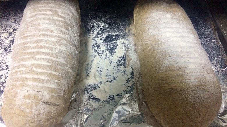 黑麦胖面包,用刀在面团表面割几刀,切成自己喜欢的形状,用筛子筛点面粉在表面装饰,我手抖放多了。