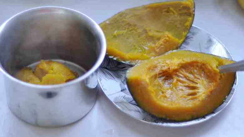 椰香牛奶南瓜糕 ,用勺把蒸熟的南瓜瓤,挖到盆里