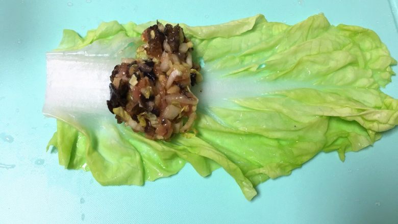 翡翠白玉猪肉卷,把白菜叶平铺在案板上,用馅料铺在菜叶子上(靠近白菜帮的那头)