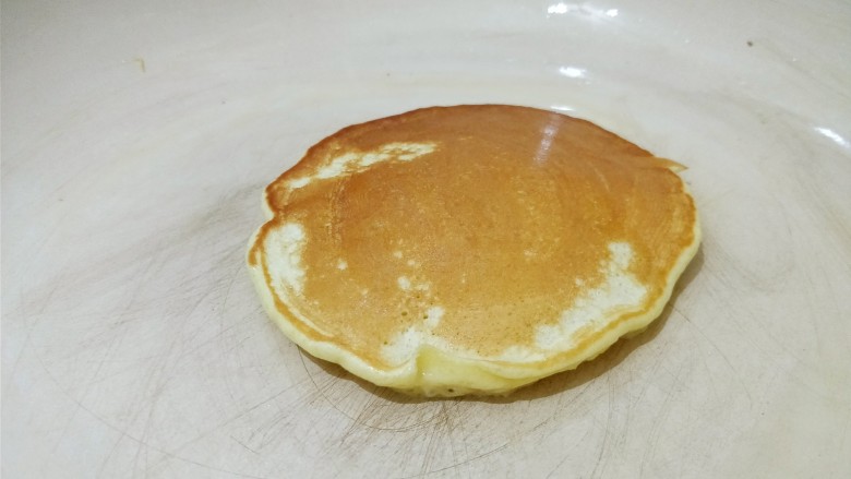 香蕉酸奶松饼,翻面后继续小火煎，用锅铲轻轻压一压。