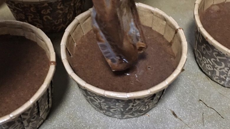 家有烤箱+快手的巧克力杯子蛋糕,将做好的面糊放入裱花袋中,裱花袋剪个口,挤入杯子里,不要挤的太满,七八分满就可以了