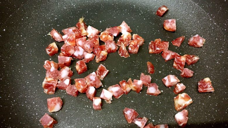 腊肠粒黄金炒饭,中火热锅,锅热后转小火,把腊肠粒放进去稍煎一下
