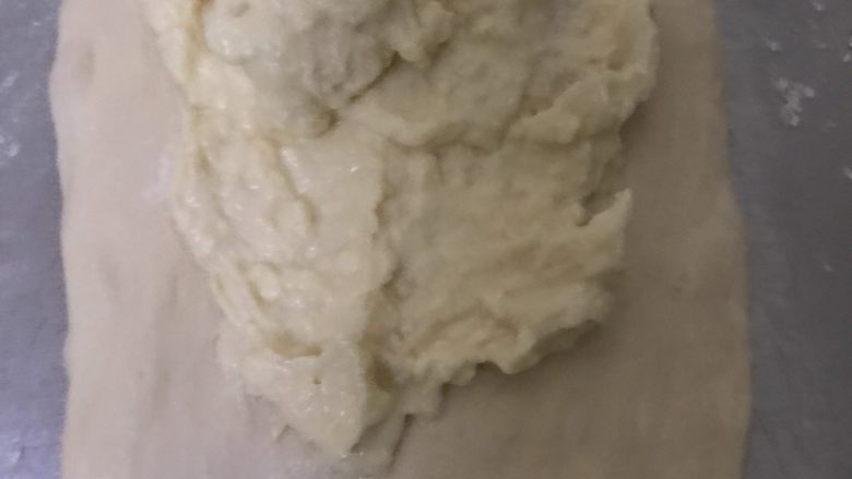 天然酵母榴莲奶酪软欧,取一个白色面团擀开，抹上榴莲奶酪馅，四周不要抹，底部留多点不要抹。