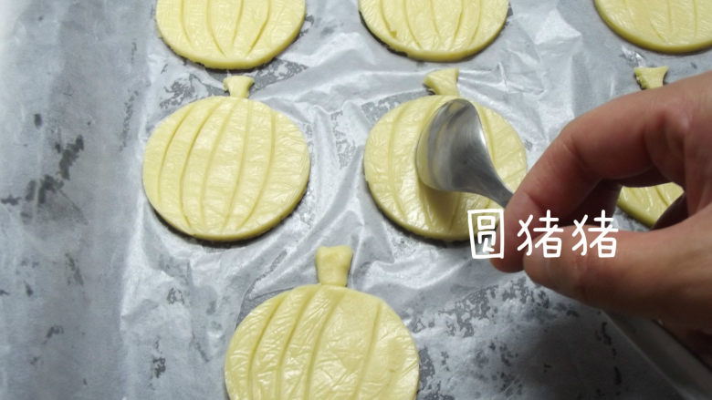 南瓜鬼脸夹心饼干,回温后的饼干,变的有些软了,取一根汤匙,在南瓜上按压出条纹状,尽量按深一点,但不要压断了。将 处理好的饼干,连同烤盘,再度放入冰箱冷冻室里。