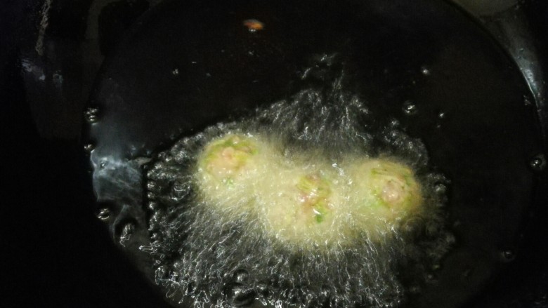 炸萝卜肉丸,锅烧热倒入适量油烧至6成热,用手挤出丸子放入锅中。
