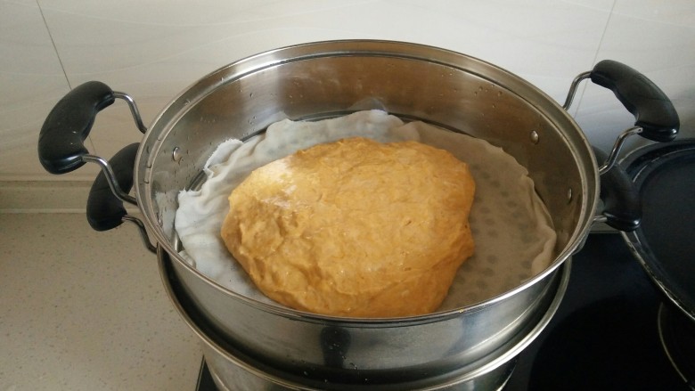 南瓜发糕,倒入南瓜面团，用刮板和手掌沾少许水（防粘）把面团表面稍稍整平。。我懒啊，可以倒入模具内，模具底和四周需要抹上油好脱模。