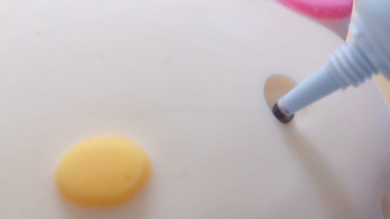 家有烤箱+hello kitty可可慕斯(附戚风蛋糕),黑色巧克力笔融化后,在模具眼睛位置挤上,速度要快,不然巧克力很快就遇冷凝固了。