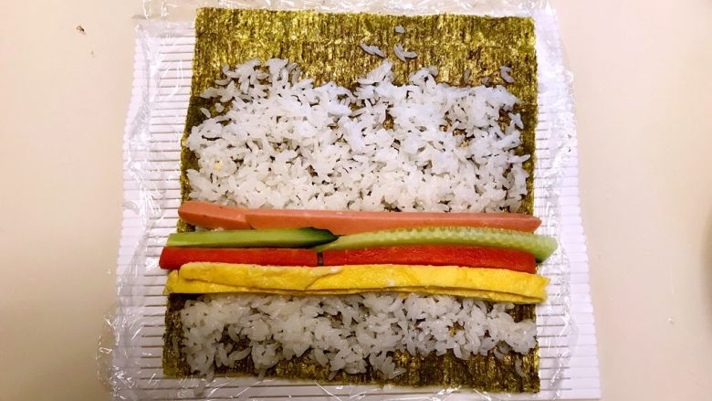 寿司,在米饭上加入蛋皮,胡萝卜条,瓜条,火腿条