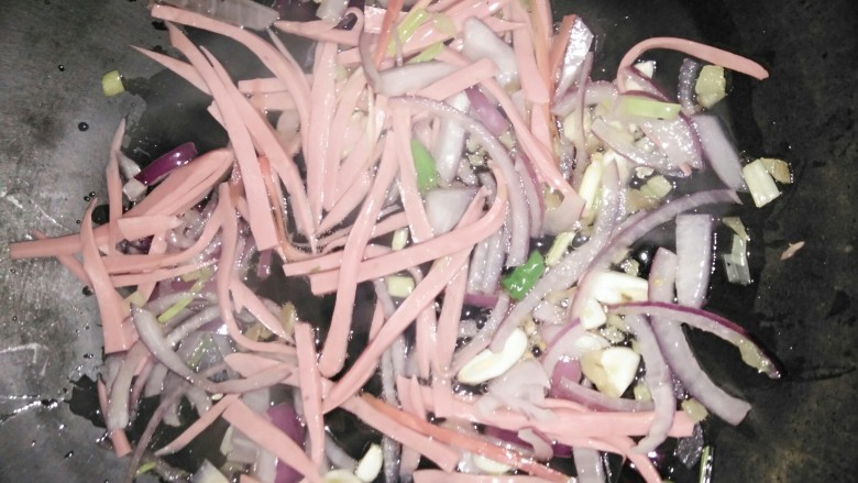 炒面,下入大蒜生姜,火腿肠