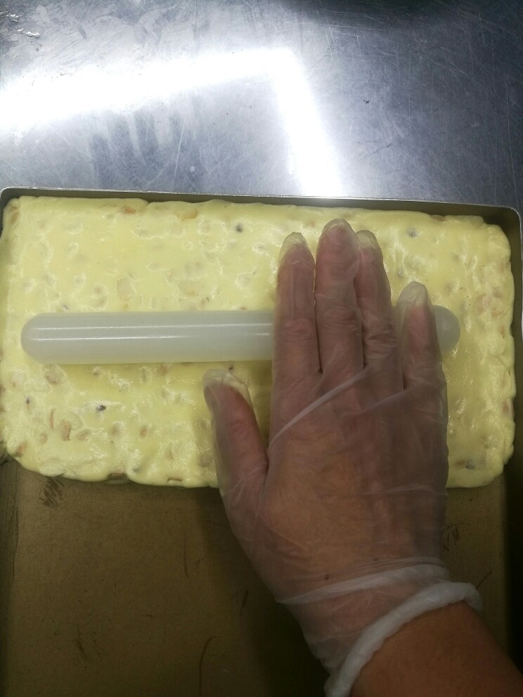 零失败的牛轧糖,放在黄金烤盘中,用擀面杖擀平整。此方的量做出的牛轧糖大约是28*14大小,也就是黄金烤盘的一半量