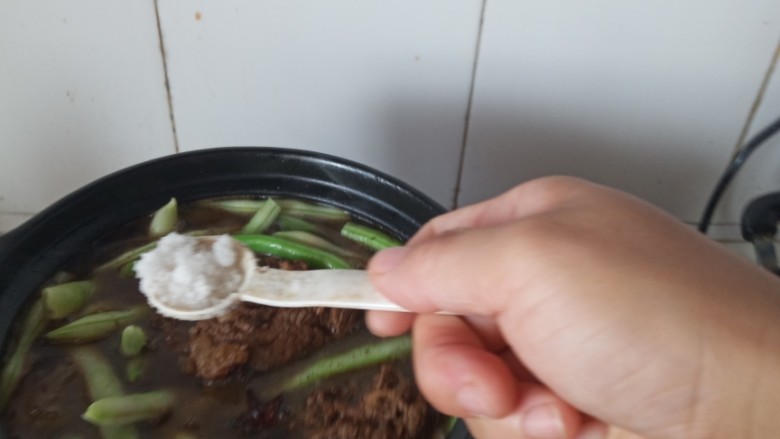 东北菜之脊骨炖豆角,加盐调味儿,继续炖煮到汤汁半干,豆角熟透即可