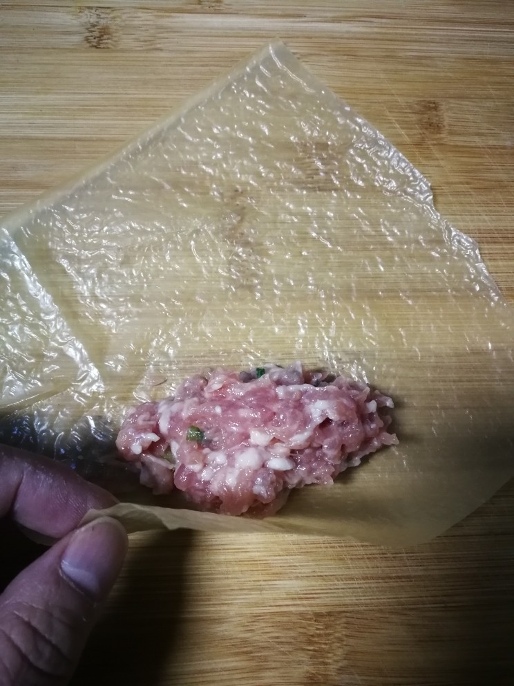 炸响铃,用四分之一张豆腐衣平铺在案板呈菱形状,在对角处放上适量肉糜。